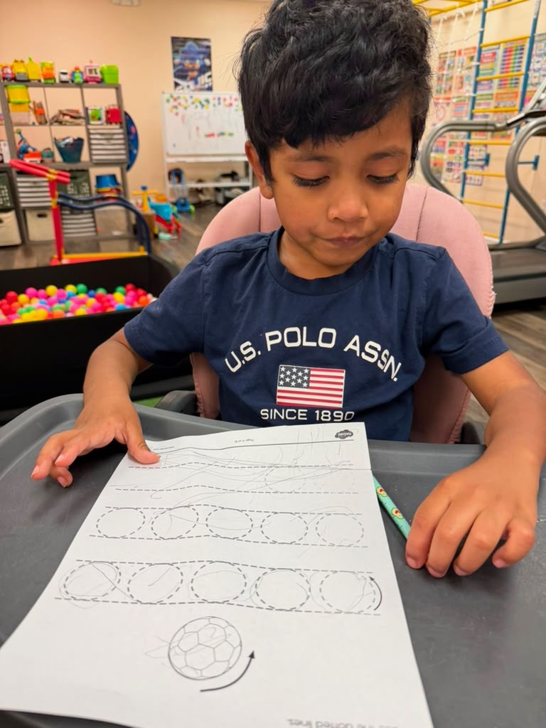Child practicing pre-writing strokes and fine motor coordination during an occupational therapy session