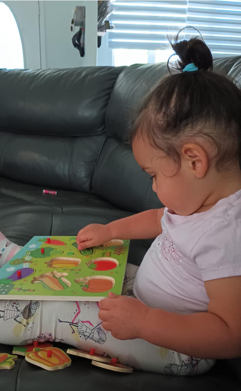 Toddler completing a wooden shape puzzle during a home therapy session