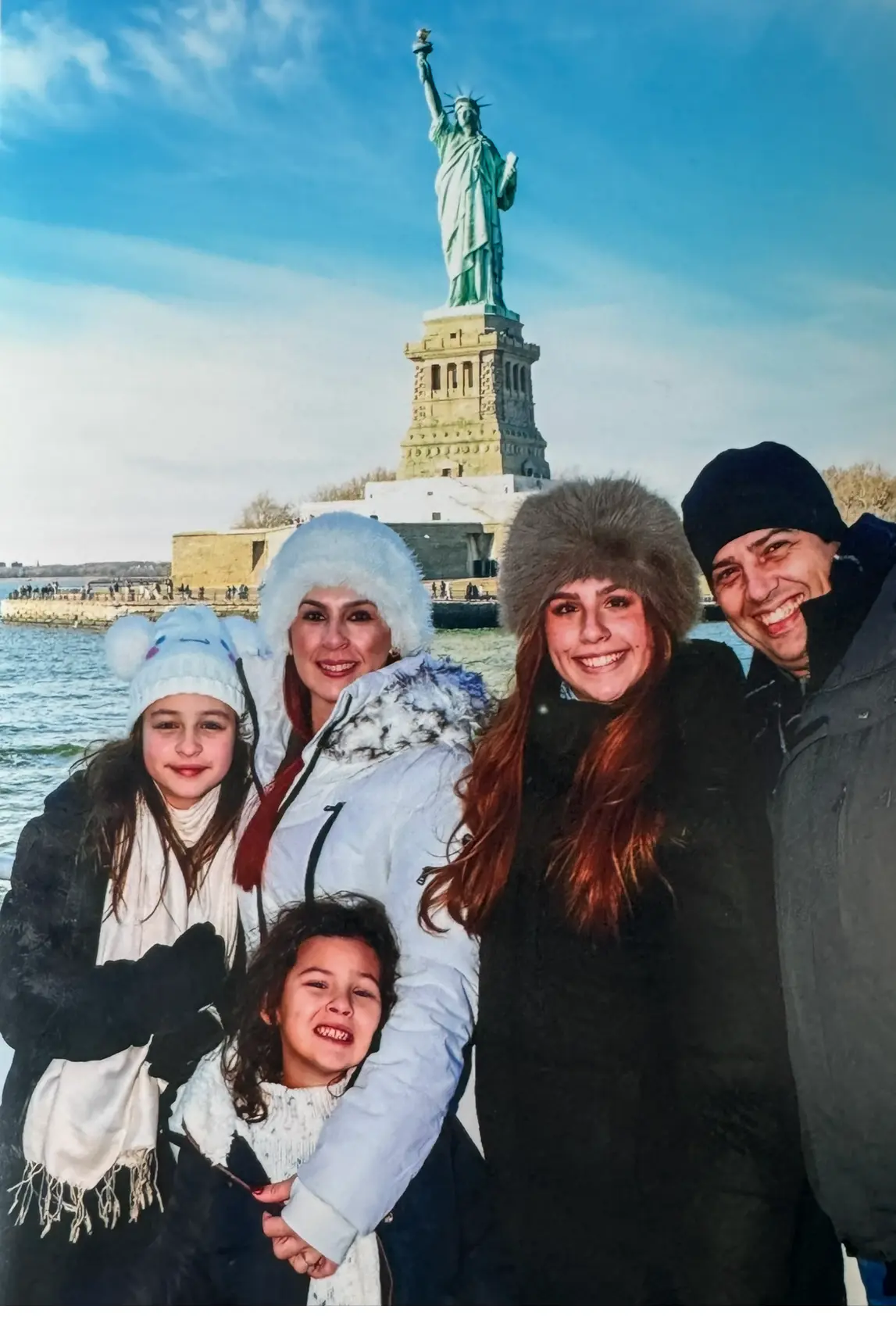The Leon family smiling together in front of the Statue of Liberty