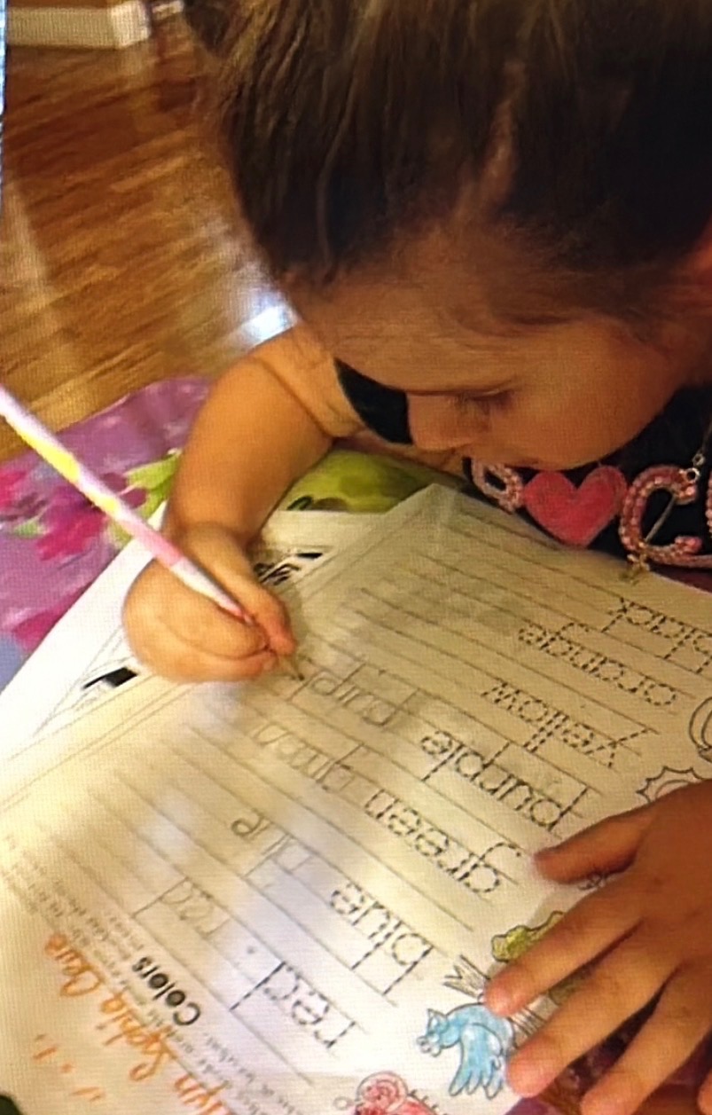 Child practicing handwriting and color words during a home therapy session